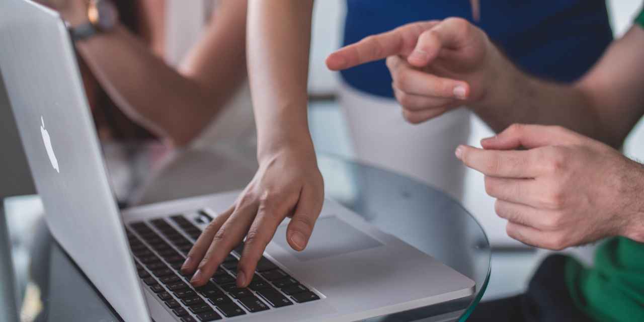 people pointing at laptop