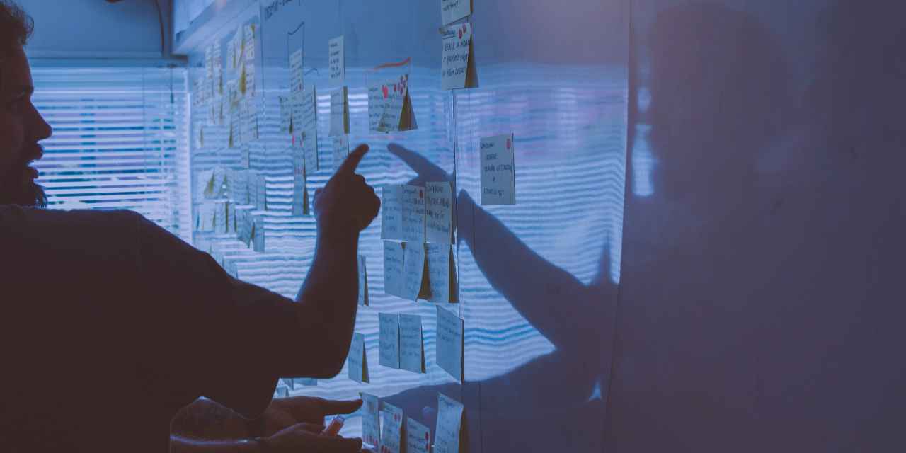 man pointing at notes on whiteboard